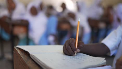 close up cinematic shot of a african black kid with a pencil writing homework at islamic school in africa 4k