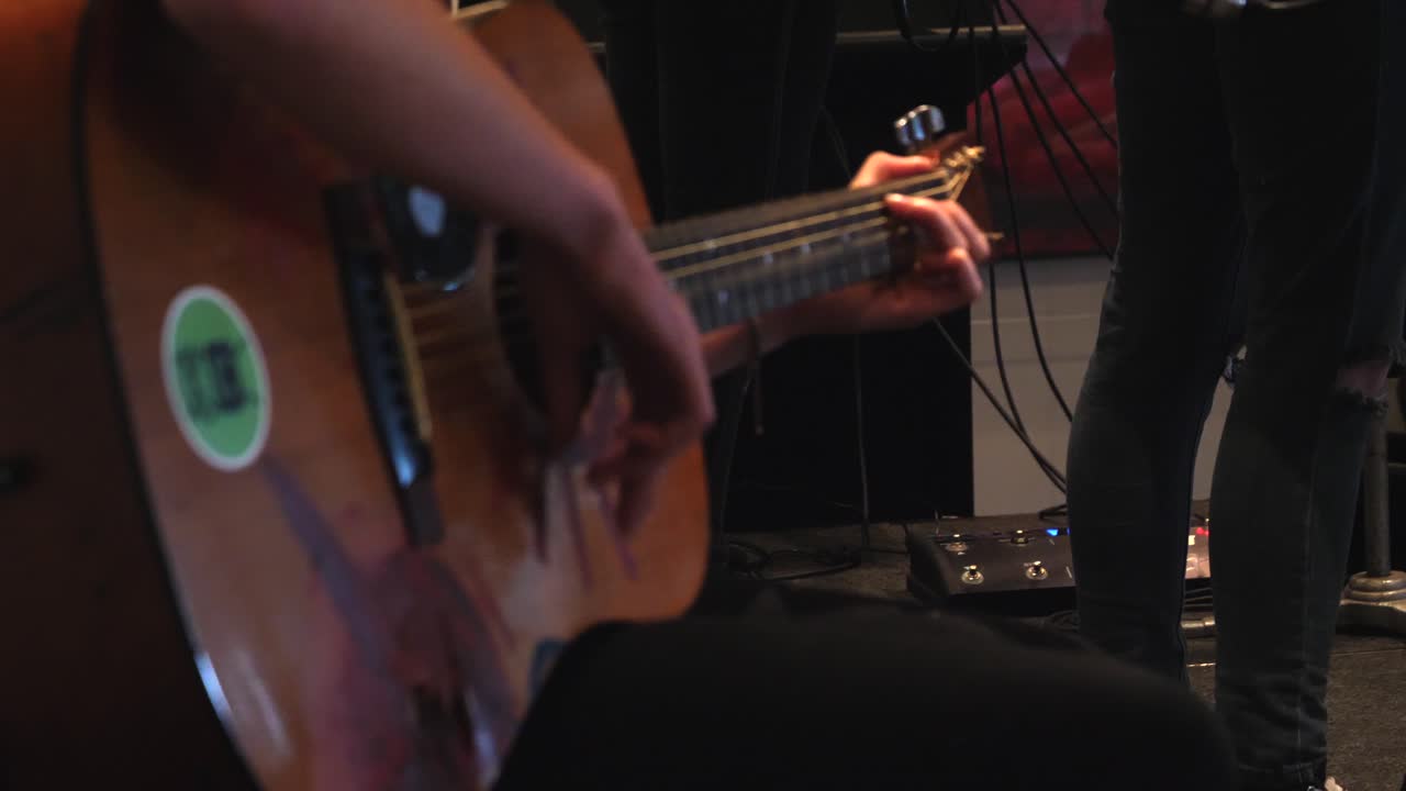 녹색 스티커로 기타를 치는 사람의 랙 포커스 슬로우 모션 공개