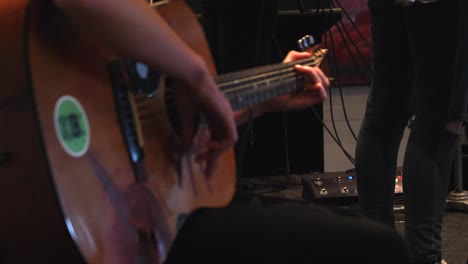 enfoque en rack, cámara lenta, revelación de una persona tocando la guitarra con una pegatina verde.