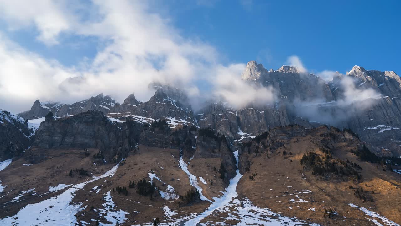 Mountain ranges switzerland. the mountain peaks are snow covered and the sun rays shine through the clouds. the clouds swirl at the peaks. Beautiful swiss landscape. Timelapse. Pure nature