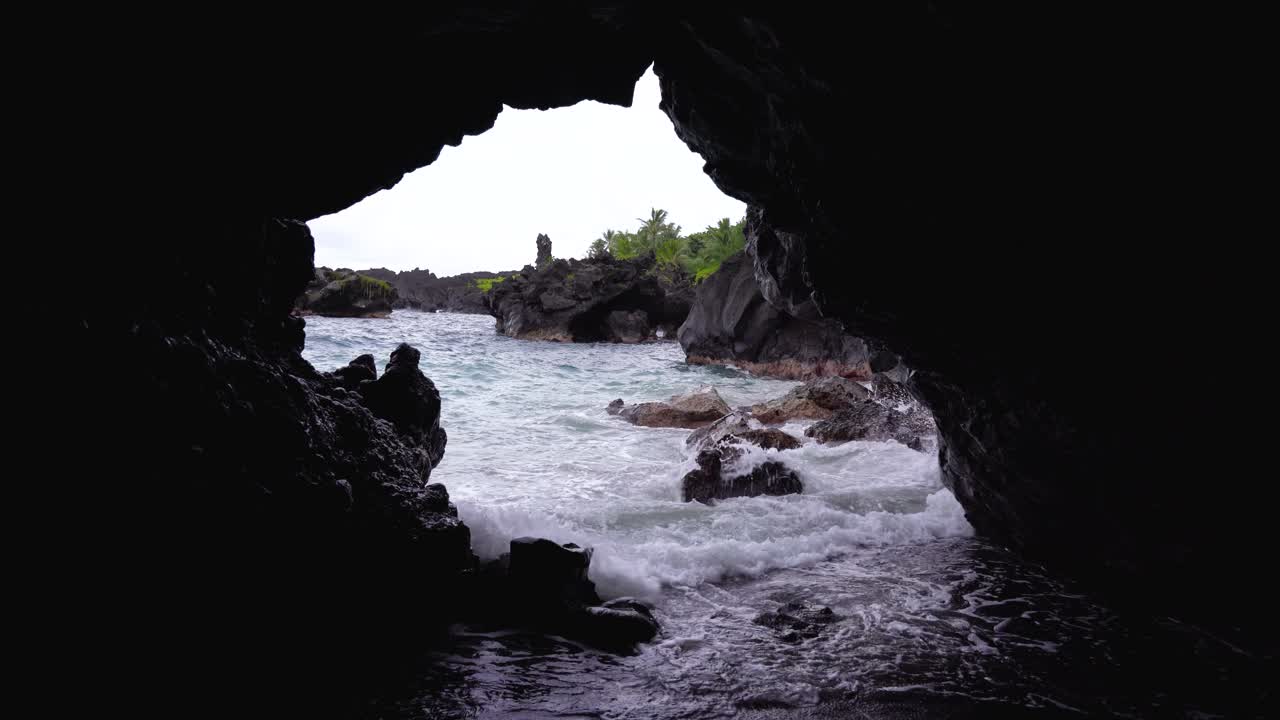 una vista de la cueva en la playa de arena negra en el parque estatal de waianapanapa a lo largo de la carretera a hana en el este de maui, hawai, un destino turístico popular a lo largo del camino a hana