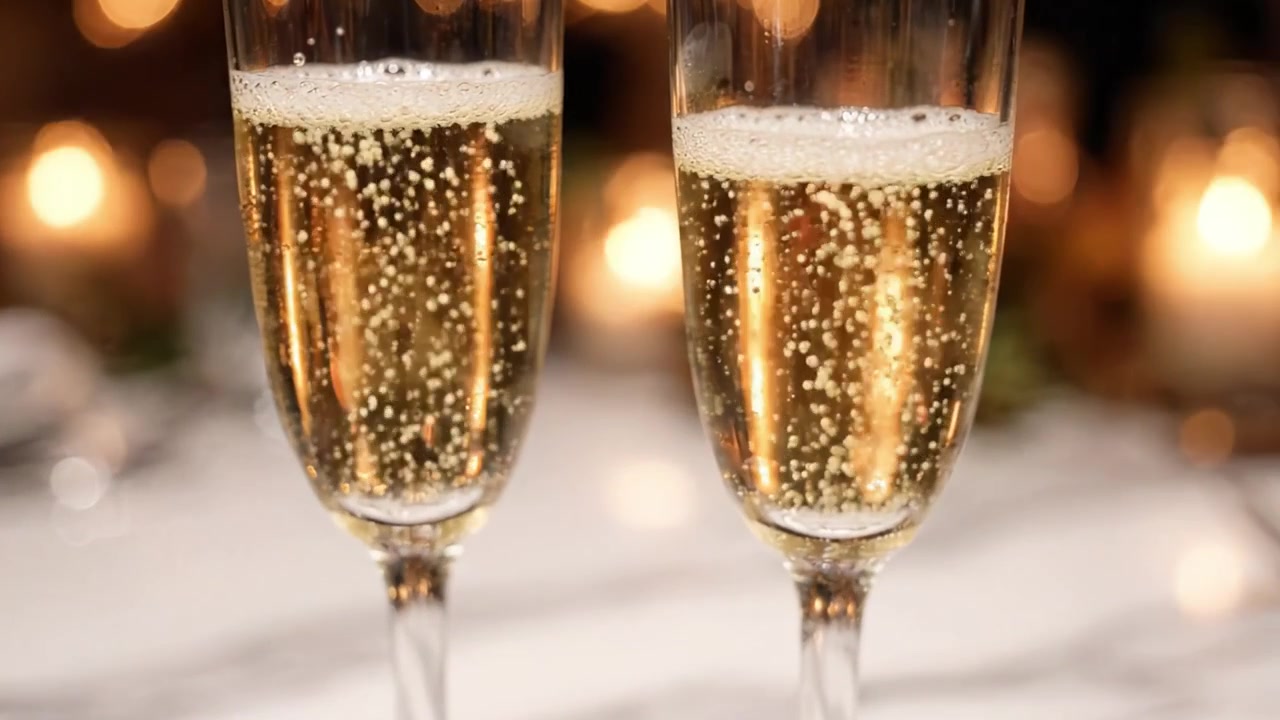 Un primo piano di due eleganti flûte di champagne riempiti di bollicine scintillanti su uno sfondo delicatamente illuminato, perfetto per celebrazioni e occasioni speciali.