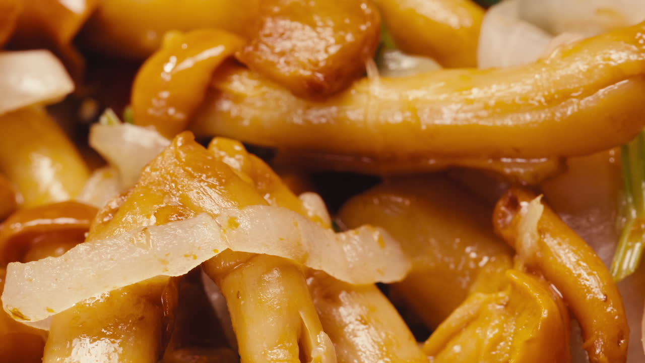 Close-up of fermented yellow honeydew mushrooms with onion on plate. Preservation of vegetables in glass jars. Fermentation preserved mushroom with spices rotating macro.