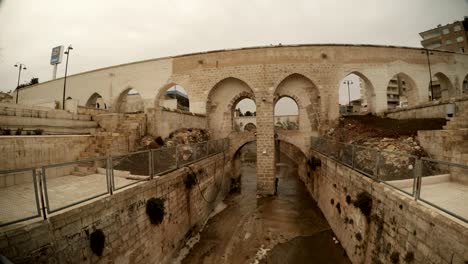 old bridge under ancient canal crows fly in sanliurfa cloudy wintry day