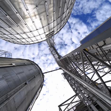 large industrial plant with storage tanks. silver grain elevators for agribusiness. modern warehouse. view from below. camera circling.