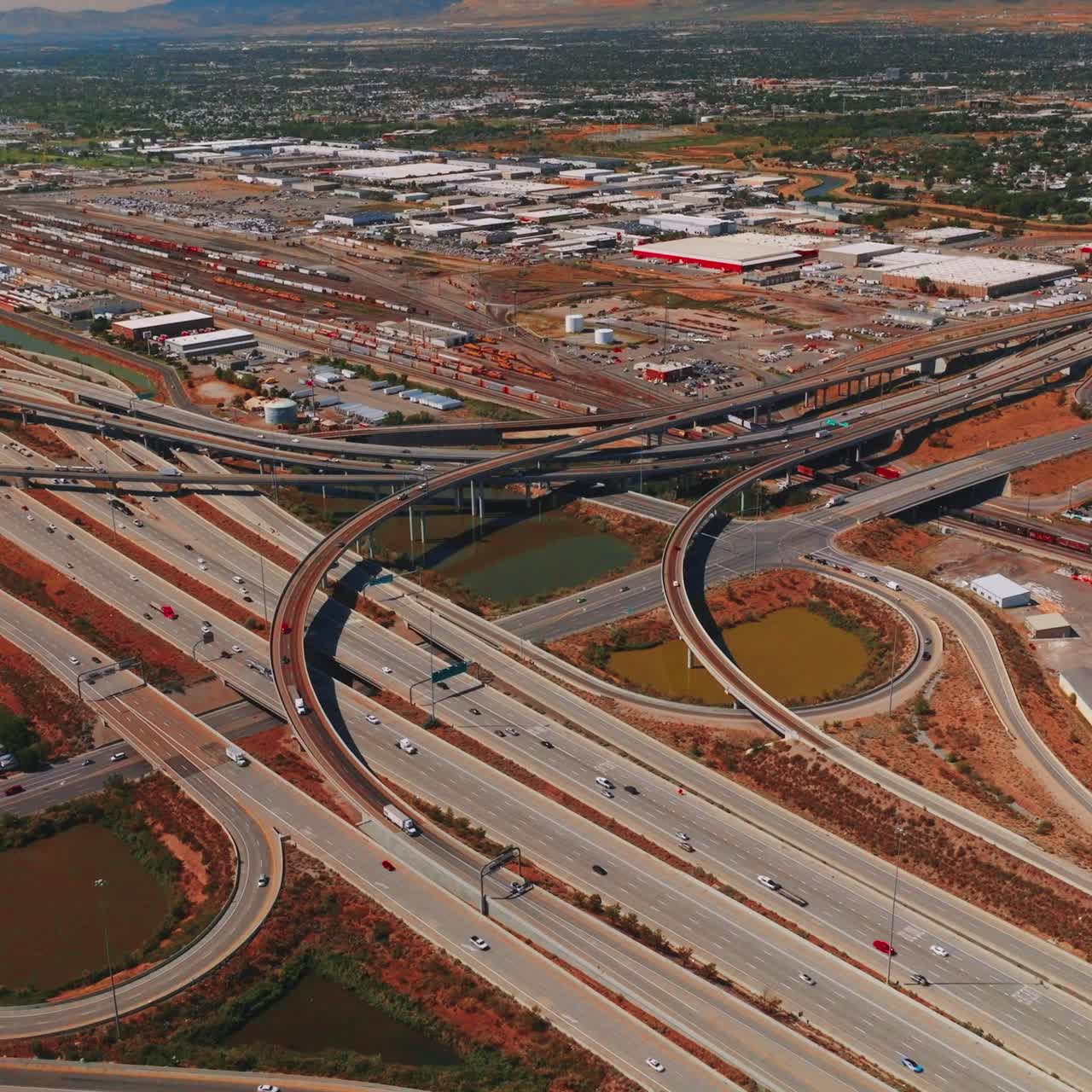 Highways and skyways with multiple cars moving by. Vast panorama of Salt Lake City on sunny bright day. Aerial perspective