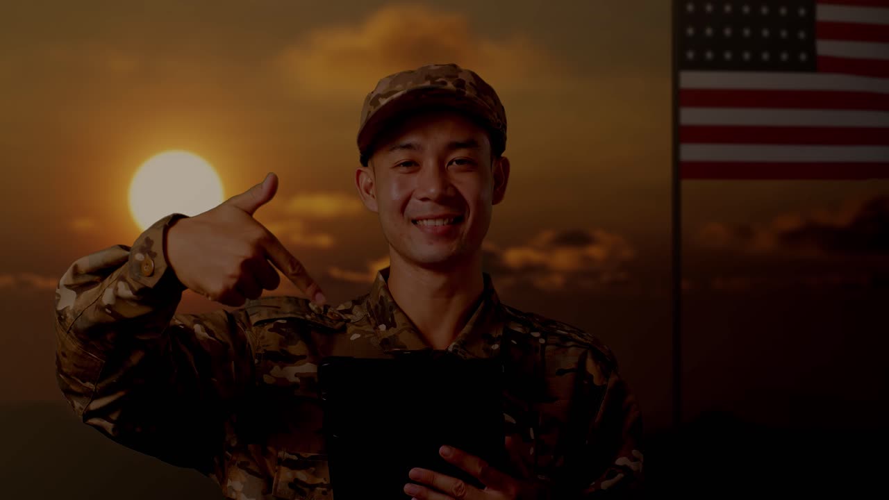 아시아 남성 군인이 미소 짓고 손에 을 가리키며 미국 발을 들고 서 있다.