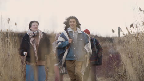 vista frontal de un grupo de adolescentes y niñas con ropa de invierno caminando en un campo de trigo en un día nublado 1