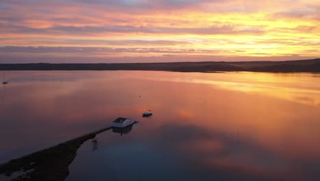 aerial drone flight over lake house at sunset in fornells bay, menorca spain