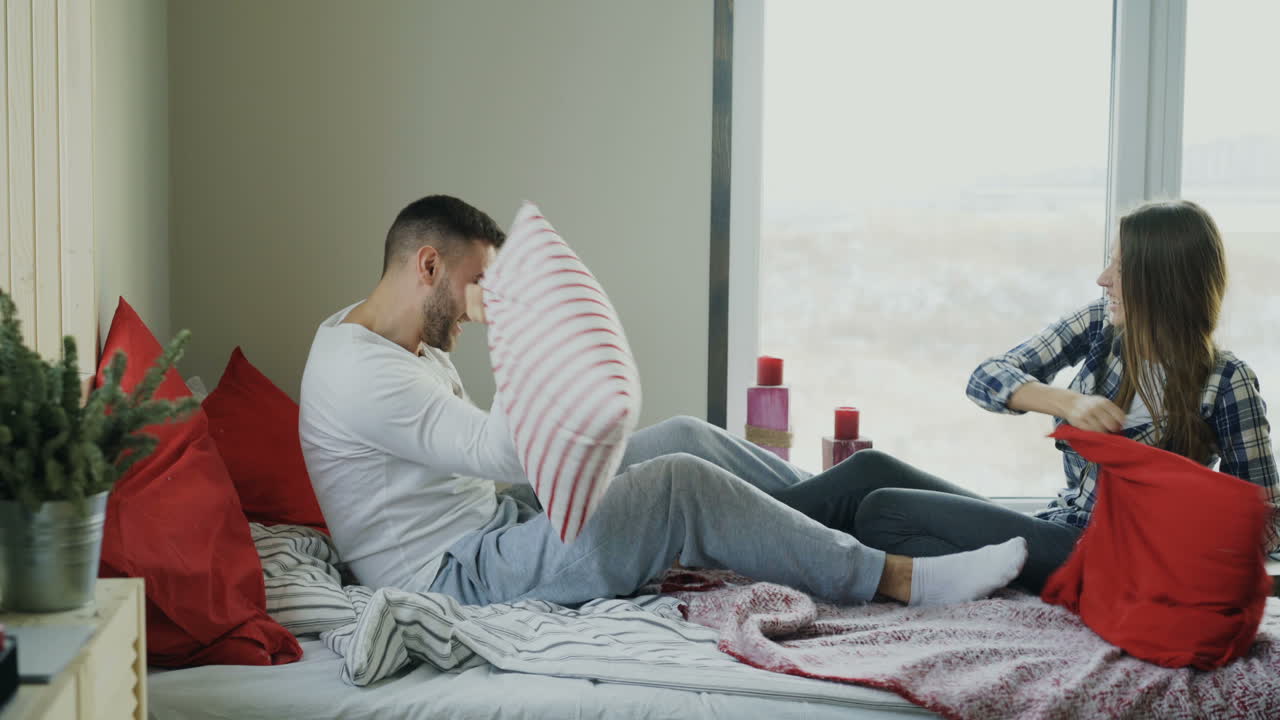 침대에서 베개 싸움을 하는 커플