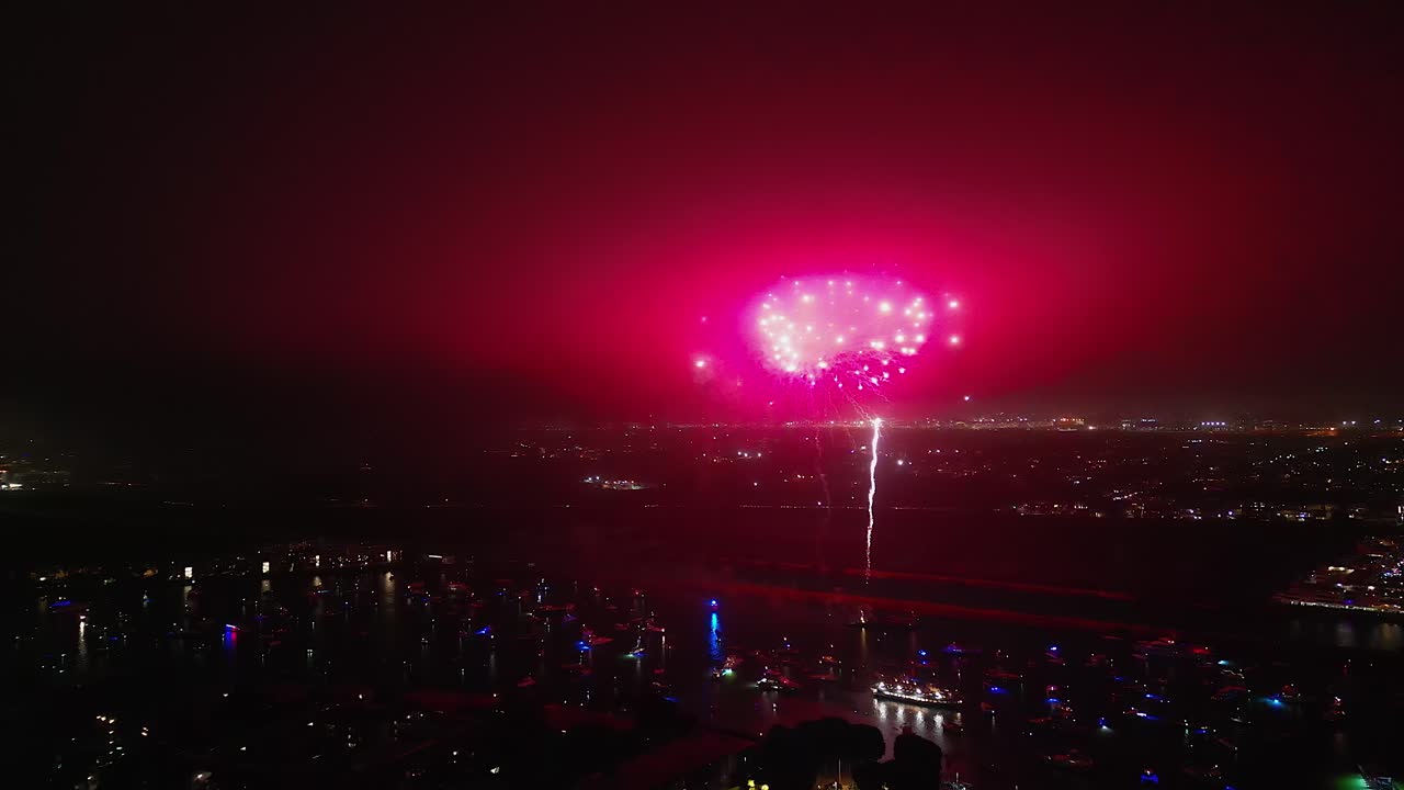 Boats moored off LA beach enjoy July 4 fireworks on dark night, aerial