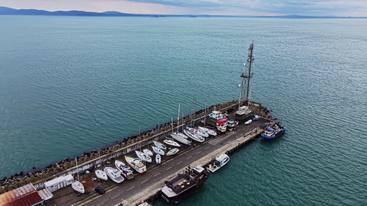 Barcos atracados en el muelle con aguas tranquilas y cielo nublado.