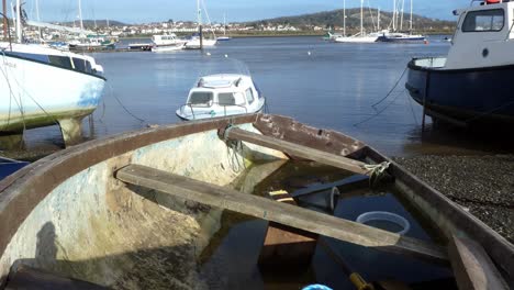 pequeño barco de pesca desgastado en la ciudad portuaria lleno de agua en desuso e inundado frente al mar