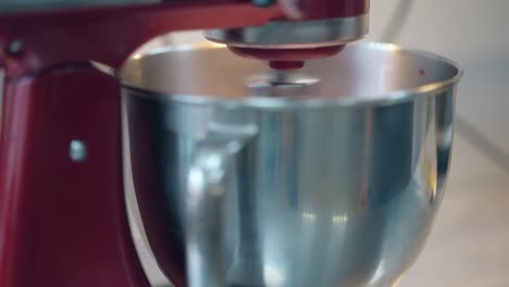 red mixer spins and prepares pink cream in large bowl