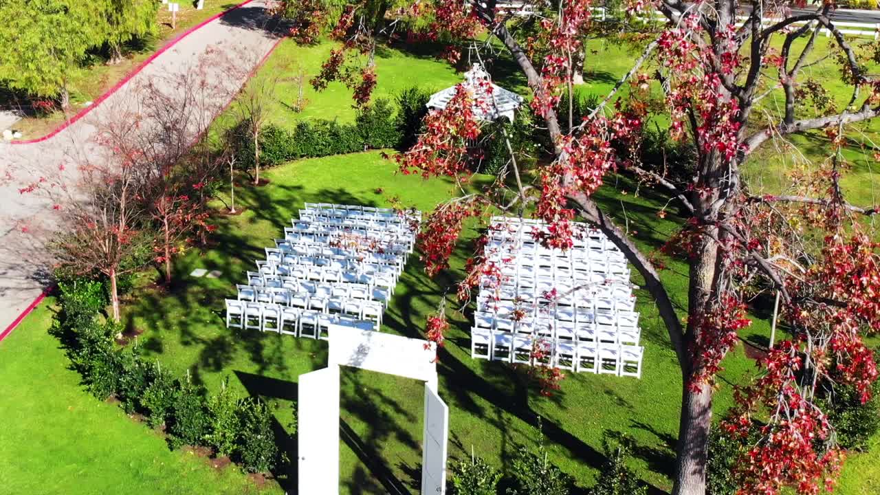 Aerial drone descending shot passing by trees showing an outdoor wedding venue