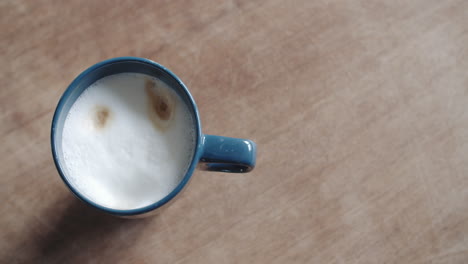 caucasian hand grabing a mug and putts it back onto the table