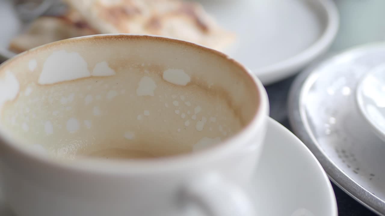 An empty coffee cup with dried residue on a saucer