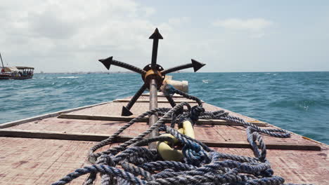 iron grappling anchor and rope on bow deck of sailing wooden boat