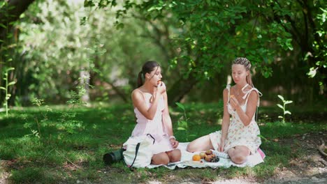 two young women having a picnic in the park on a sunny summer day