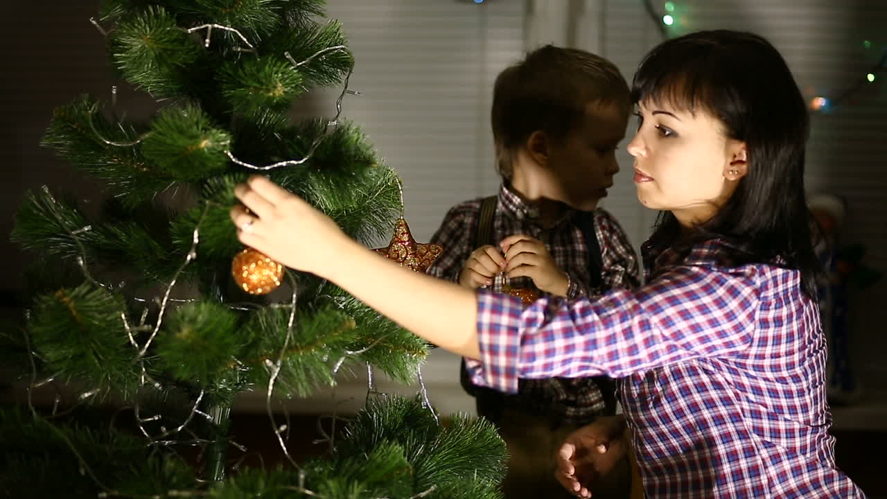 Boy Helping His Mom. Little boy helping his mom to decorate Christmas tree