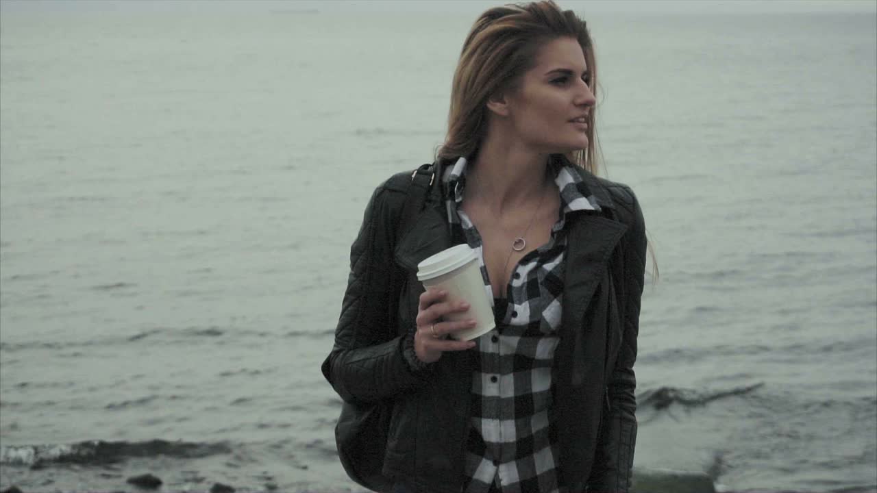mujer con café junto al mar