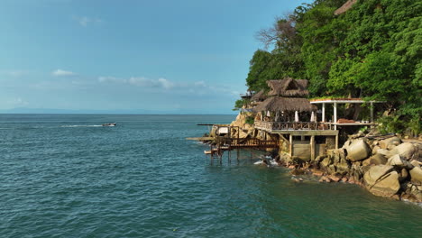 drone shot passing seaside bungalows in sunny puerto vallarta, mexico