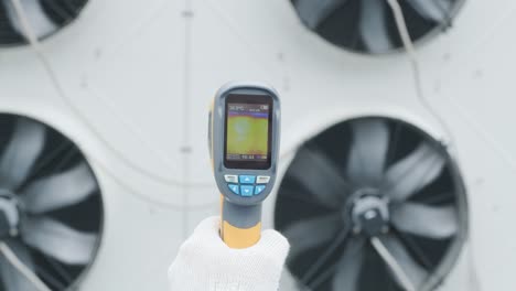 technician uses a thermal imaging infrared thermometer to check the condensing unit heat exchanger