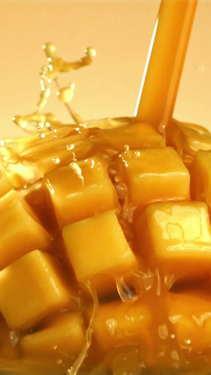 Versamento di succo al rallentatore su cubetti di mango fresco