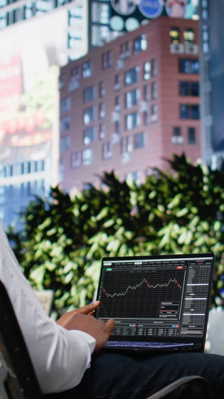 Vertical Video Black man navigating stock trading indicators online on laptop