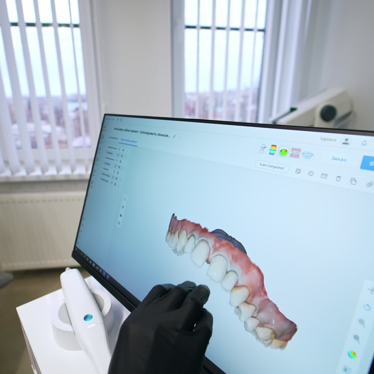 Dentist's hand in latex black glove moving the 3d picture of patient's denture on the big sensor screen. Doctor rotating the teeth projection to show the dental problems to a patient. Close up