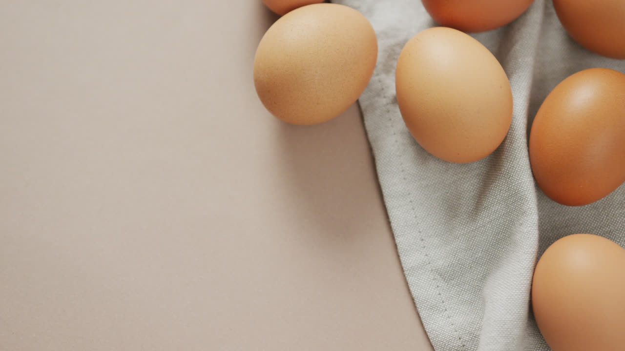 Video of overhead view of eggs and on rustic cloth on beige background