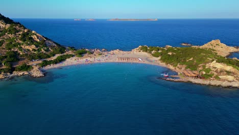 aerial drone backward moving shot over tourists sunbathing on breathtaking punta molentis beach, villasimius, south sardinia, italy on a sunny day