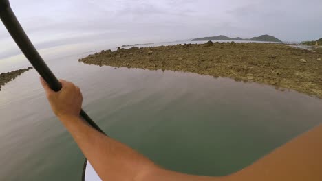 pov footage of a paddle boarder rowing through a narrow stream during sunset in koh samui