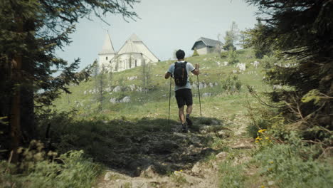 hiker walking up a hill, church and a house at the top, thin clouds on the sky