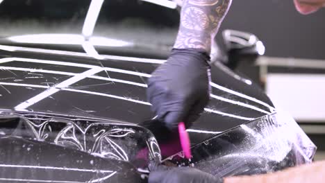 hombre que cubre el coche con cinta de poliuretano de vinilo. películas para el coche. pegatina película protectora en el coche
