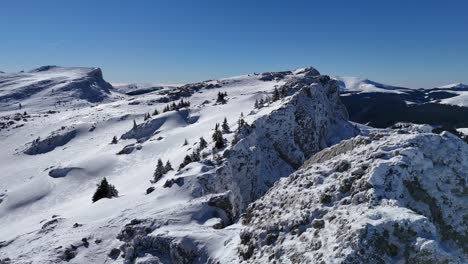 snow-covered strungile mari peak in the bucegi mountains under a clear blue sky, aerial view