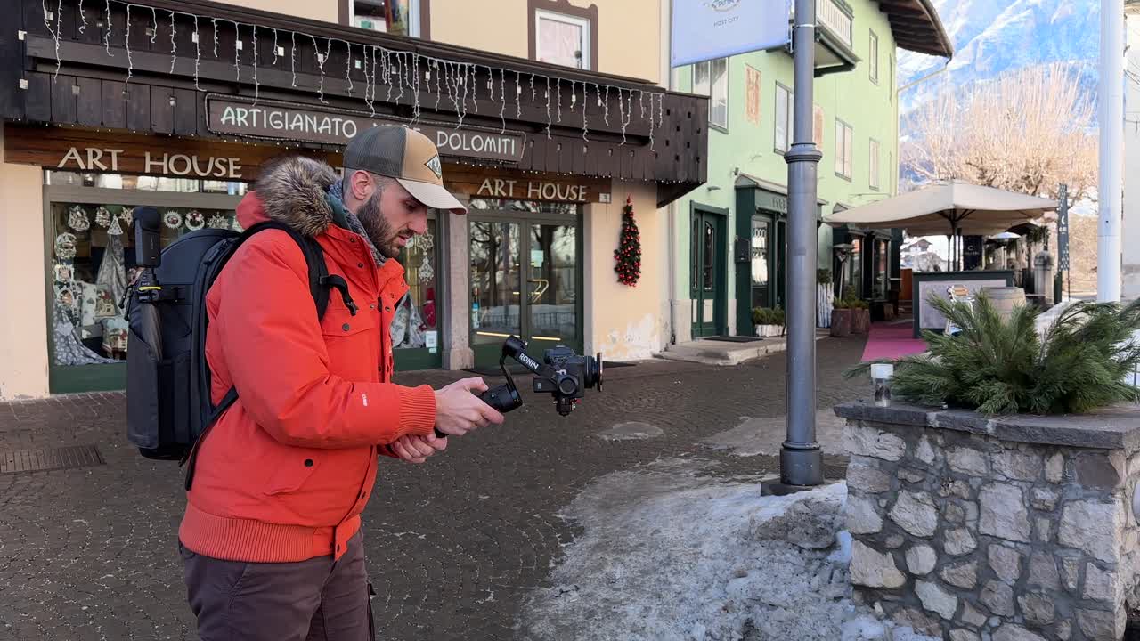 Professional vlogger holding camera mounted on stabilizing gimbal DJI RS3 Mini, Cortina d'Ampezzo in Italy