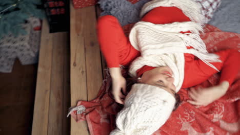 pretty lady in white hat and scarf poses laying on bed. christmas spirit video.