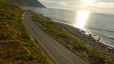 fpv drone shot over a beautiful coastal road at kogel bay during sunset