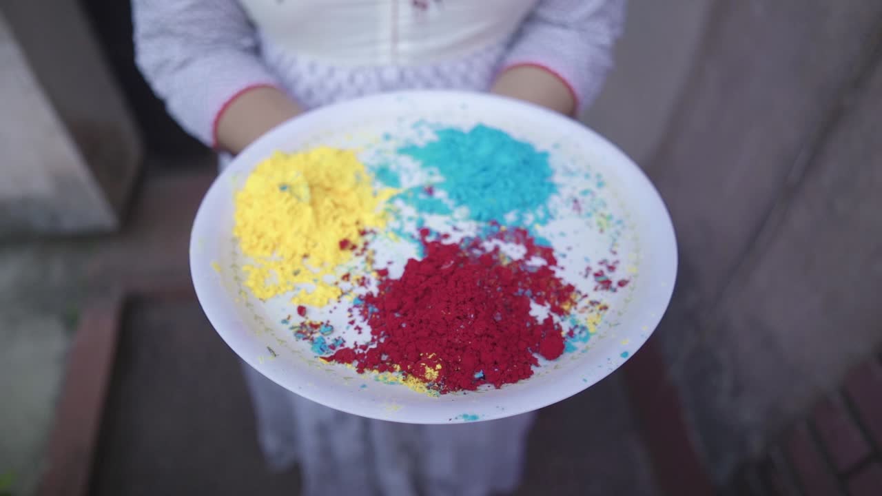 Unrecognizable girl holds tray of colored powders on Holi outdoor, slow motion