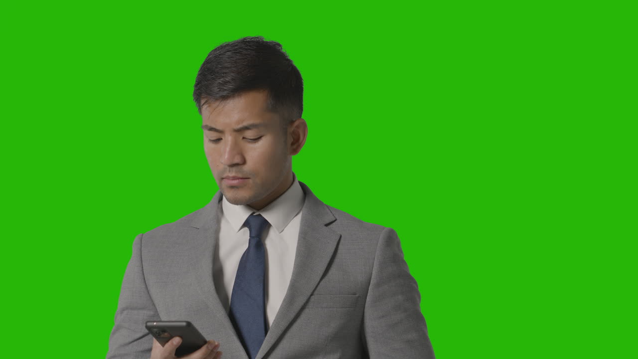 녹색 화면에 대해 휴대 전화로 전화를 받는 소송에서 심각한 사업가의 스튜디오 샷