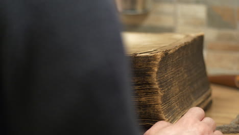 person opens dusty old book next to rusty key, medium