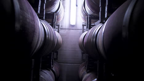 drone descend between stack of traditional oak wine barrels in a rack house