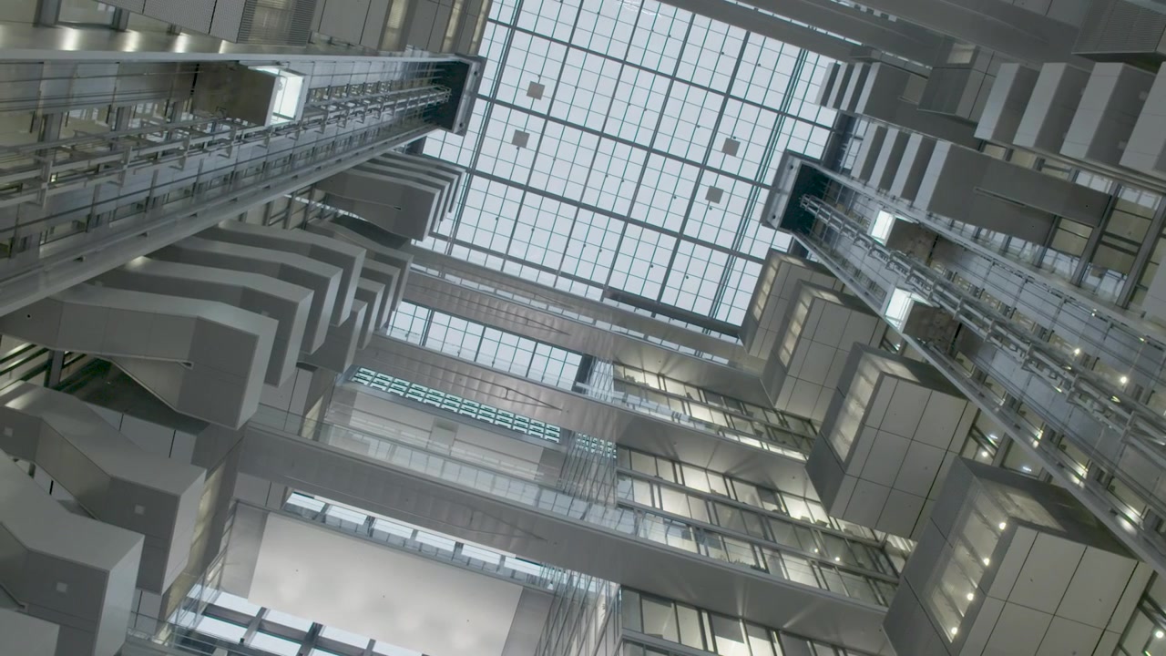 Mirando hacia arriba ascensores de cristal modernos y arquitectura geométrica dentro de un atrio luminoso