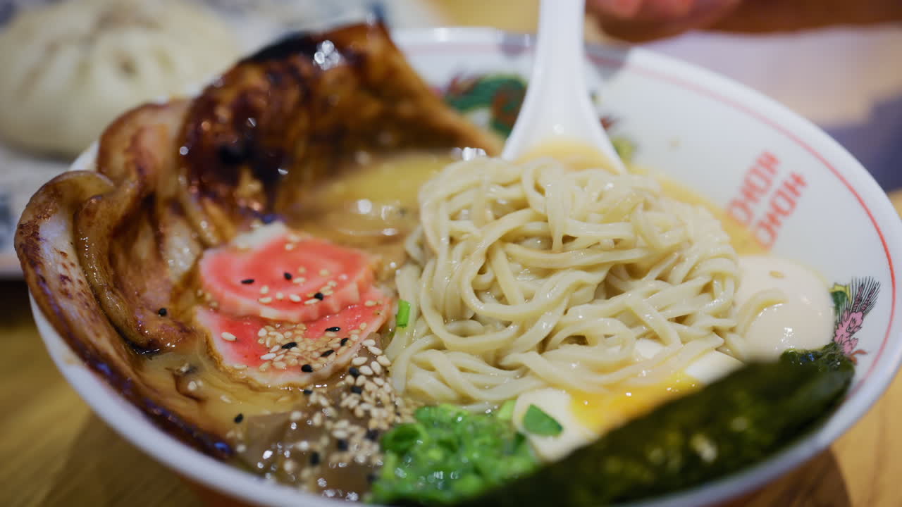 Primo piano di un cucchiaio che solleva ramen mostrando i condimenti e il brodo fumante