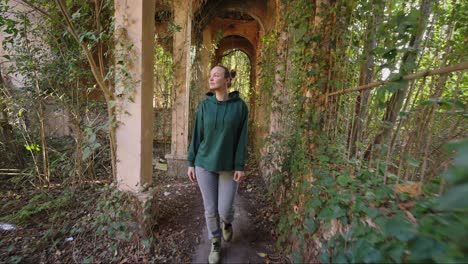 woman exploring an abandoned garden corridor
