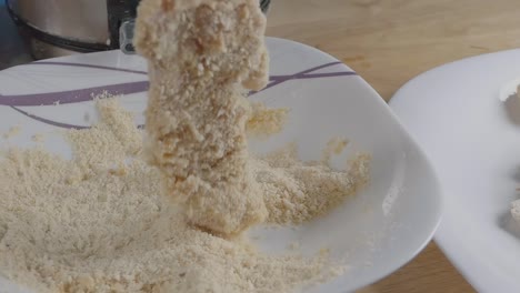 toma deslizante en cámara lenta de trozos de pechuga de pollo empanizados con un tazón de pan rallado en la cocina