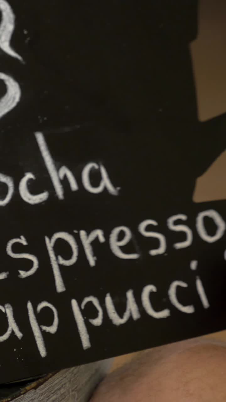 Nærbillede af hånd, der skriver "Cappuccino" på en kridttavle