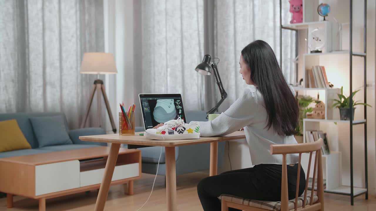 가정 사무실에서 노트북으로 신발을 디자인하는 여성