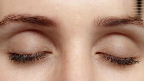 ojos cerrados mujer aplicando maquillaje máscara usando cosméticos pincel macro